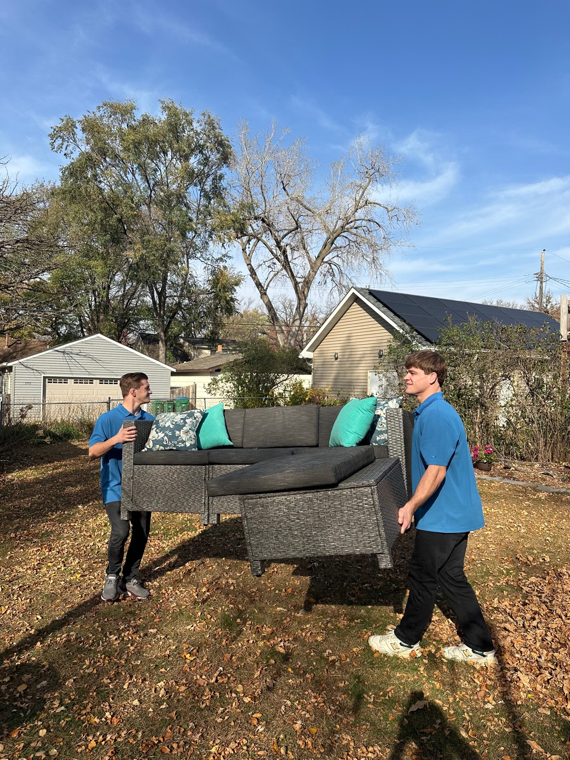 Junk Genies crew carrying a sectional couch out of a yard